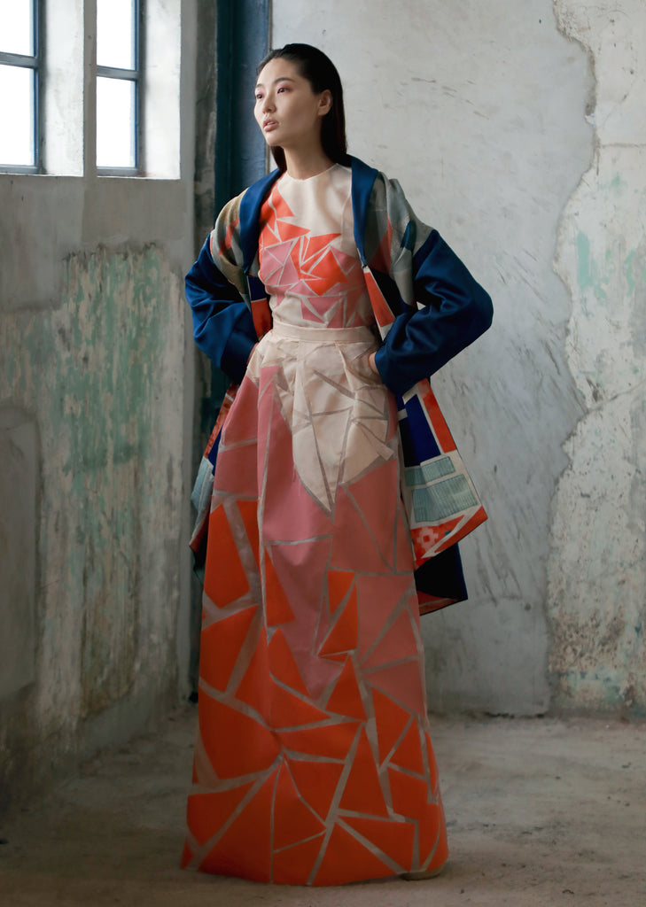 woman wearing blue patchwork boro coat and floor-length geometric skirt with matching orange pink white geometric top